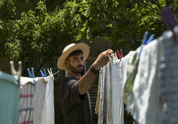 Man hanging up laundry outdoors - VEGF00886