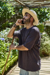 Mann mit Besen benutzt sein Smartphone im Freien - VEGF00892