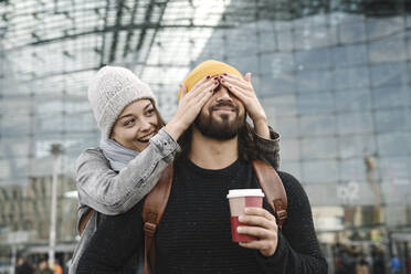 Glückliche junge Frau, die ihren Freund am Hauptbahnhof überrascht, Berlin, Deutschland - AHSF01410