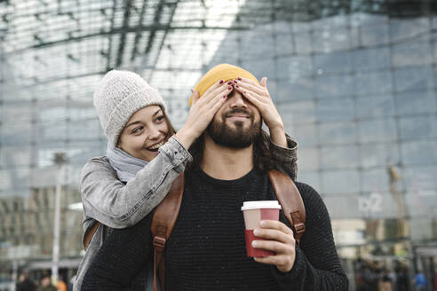 Happy young woman surprising boyfriend at the central station, Berlin, Germany - AHSF01410