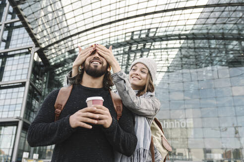 Glückliche junge Frau, die ihren Freund am Hauptbahnhof überrascht, Berlin, Deutschland - AHSF01411