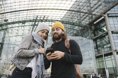 Junges Paar benutzt ein Smartphone am Hauptbahnhof, Berlin, Deutschland, lizenzfreies Stockfoto