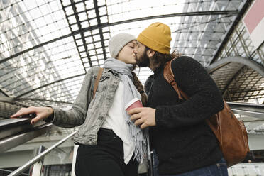 Junges Paar, das sich auf einer Rolltreppe am Bahnhof küsst, Berlin, Deutschland - AHSF01421