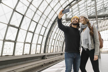 Glückliches junges Paar macht ein Selfie auf dem Bahnsteig, Berlin, Deutschland - AHSF01437