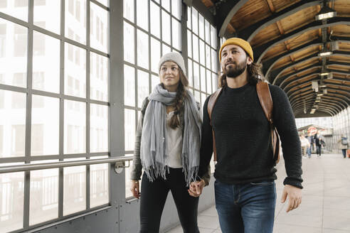 Young couple walking hand in hand at a subway station, Berlin, Germany - AHSF01440