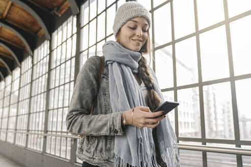 Junge Frau mit Smartphone auf dem Bahnsteig, Berlin, Deutschland - AHSF01441