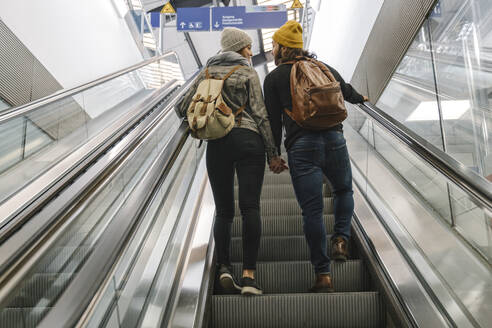 Rear view of young couple on an escalator at the station, Berlin, Germany - AHSF01446