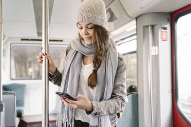 Junge Frau benutzt Smartphone in einer U-Bahn - AHSF01456