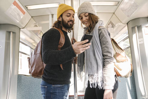 Junges Paar benutzt Smartphone in einer U-Bahn - AHSF01457