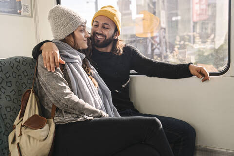 Glückliches junges Paar sitzt in einer U-Bahn, lizenzfreies Stockfoto