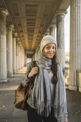 Portrait of smiling young woman in arcade in the city, Berlin, Germany - AHSF01479
