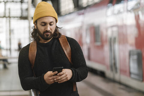 Junger Mann mit Smartphone auf dem Bahnsteig, Berlin, Deutschland, lizenzfreies Stockfoto