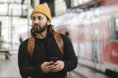 Junger Mann mit Smartphone auf dem Bahnsteig, Berlin, Deutschland, lizenzfreies Stockfoto