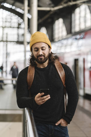 Junger Mann mit Smartphone auf dem Bahnsteig, Berlin, Deutschland, lizenzfreies Stockfoto