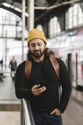 Junger Mann mit Smartphone auf dem Bahnsteig, Berlin, Deutschland - AHSF01504