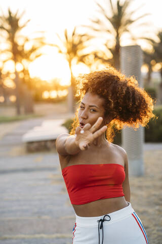 Junge glückliche Frau, die mit den Fingern eine V-Geste ausführt, lizenzfreies Stockfoto