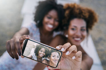 Junge Frauen lächeln und machen ein Selfie mit ihrem Smartphone in einem Park - MPPF00317