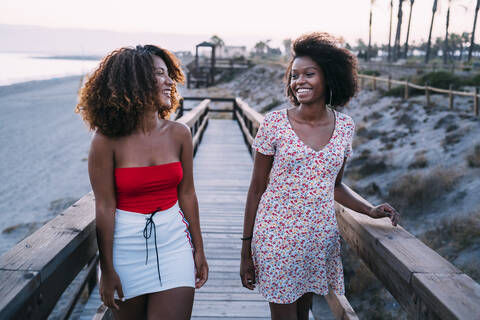 Junge lächelnde Frauen gehen zusammen in der Nähe des Strandes, lizenzfreies Stockfoto