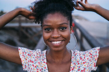 Porträt einer glücklichen Frau beim Binden der Haare - MPPF00325