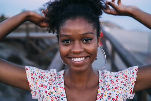 Portrait of happy woman tying hair - MPPF00325