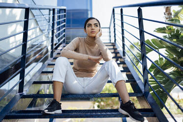 Young woman sitting on exterior stairs - JSMF01370