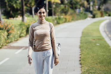 Smiling young woman walking on a path - JSMF01372