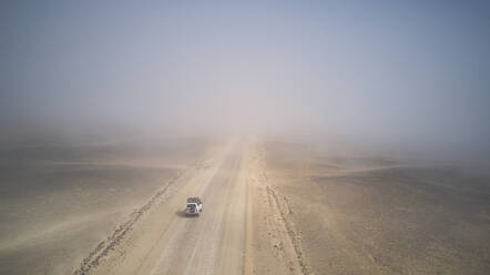 Drohnenansicht eines Geländewagens in der nebligen Wüste, Namibia - VEGF00907