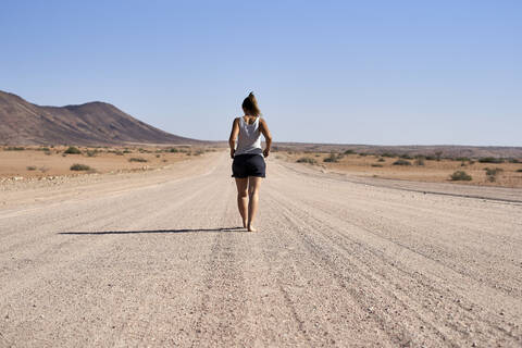 Frau geht in der Mitte einer unbefestigten Straße, Damaraland, Namibia, lizenzfreies Stockfoto