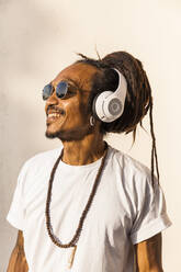 Porträt eines reifen Mannes mit Dreadlocks und Kopfhörern, der Musik hört und zur Seite schaut - TCF06209