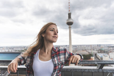 Frau auf einer Aussichtsterrasse mit Fernsehturm im Hintergrund, Berlin, Deutschland, lizenzfreies Stockfoto