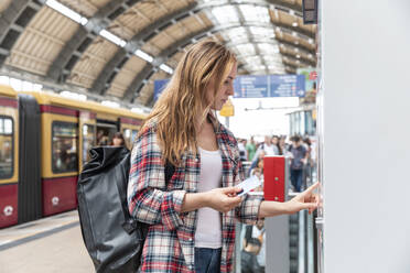 Woman at train station buying train tickets, Berlin, Germany - WPEF02304