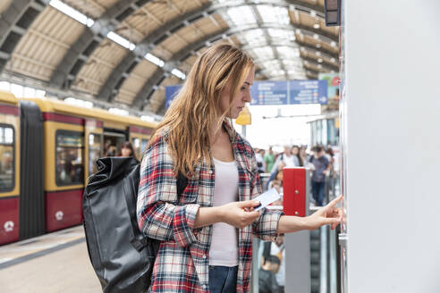 Frau am Bahnhof beim Kauf von Zugfahrkarten, Berlin, Deutschland - WPEF02304