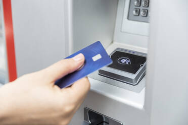 Close up of hand holding credit card and making contactless payment - WPEF02306