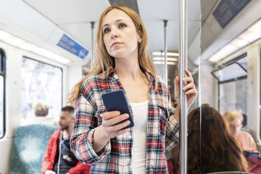 Woman with smartphone on the subway, Berlin, Germany - WPEF02307