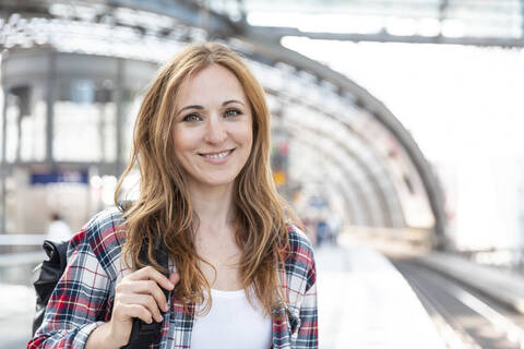 Porträt einer lächelnden Frau auf dem Bahnsteig, Berlin, Deutschland, lizenzfreies Stockfoto