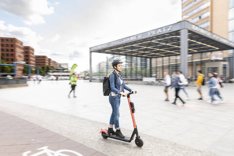 Frau fährt E-Scooter in der Stadt, Berlin, Deutschland, Berlin, Deutschland, lizenzfreies Stockfoto