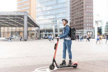 Glückliche Frau fährt E-Scooter in der Stadt, Berlin, Deutschland, Berlin, Deutschland - WPEF02342