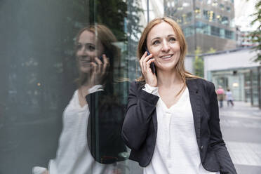 Smiling businesswoman on the phone in the city - WPEF02362