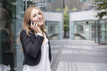 Smiling businesswoman on the phone in the city - WPEF02363