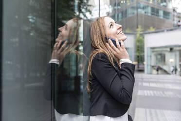 Lächelnde Geschäftsfrau am Telefon in der Stadt - WPEF02364