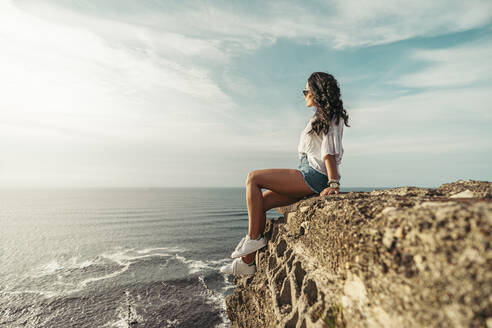 Junge Frau sitzt auf einem Aussichtspunkt und schaut in die Ferne, Getxo, Spanien - MTBF00235