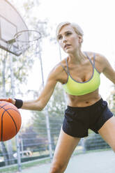 Blonde Frau spielt Basketball, dribbelt - MADF01416