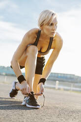 Blonde Frau beim Joggen, Schuhe binden - MADF01420