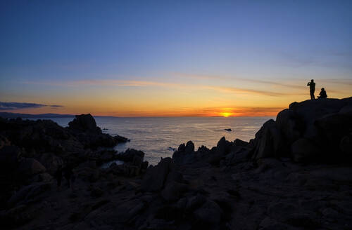 Italien, Provinz Sassari, Santa Teresa Gallura, Silhouette eines Paares, das den Sonnenuntergang über dem Mittelmeer von der Spitze des Kap Testa bewundert - MRF02298