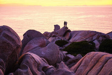 Italy, Province of Sassari, Santa Teresa Gallura, Silhouette of couple admiring sunset over Mediterranean Sea from top of Cape Testa - MRF02300