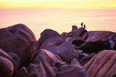 Italy, Province of Sassari, Santa Teresa Gallura, Silhouette of couple descending boulders of Cape Testa - MRF02301