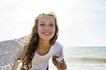 Lächelndes Mädchen mit Handtuch am Strand, Toskana, Italien - OJF00358