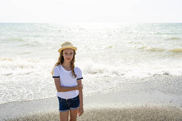 Girl with straw hat standing on the beach, Tuscany, Italy - OJF00359