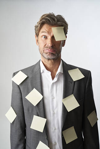 Portrait of helpless businessman with note papers stucking on his forehead and his suit coat stock photo