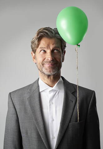 Portrait of smiling businessman with green balloon stock photo